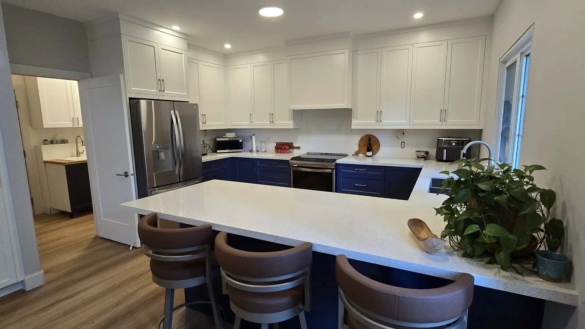 Finished MATCON kitchen with blue lower cabinets and a white island.