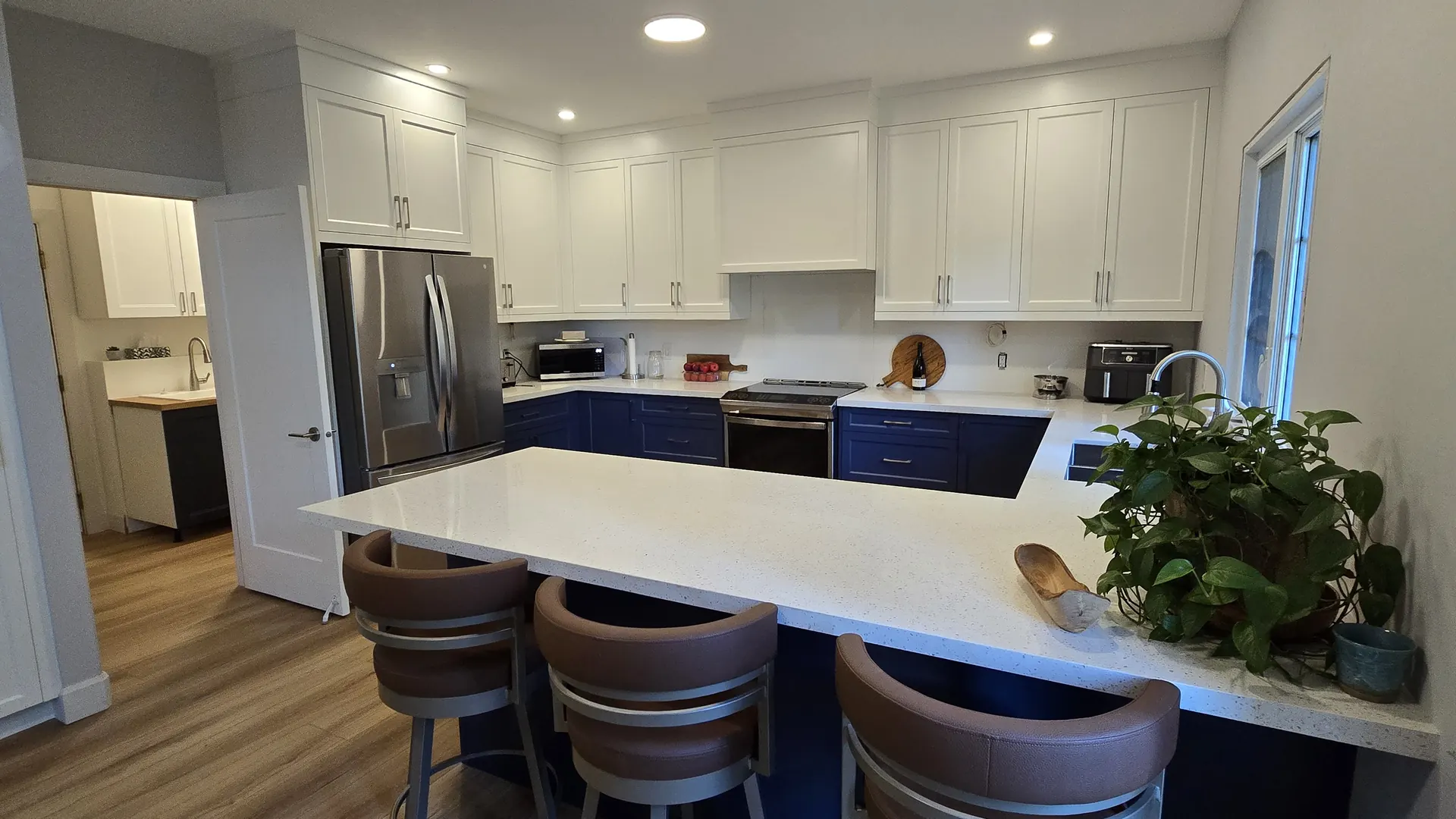 Finished MATCON kitchen with blue lower cabinets and a white island.