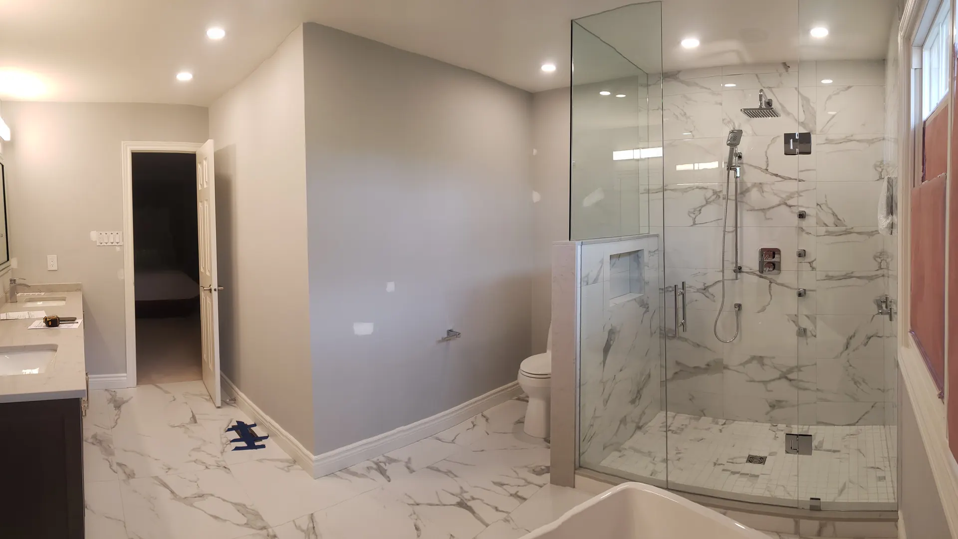 Finished MATCON bathroom renovation with marble tile, glass shower, and freestanding tub.