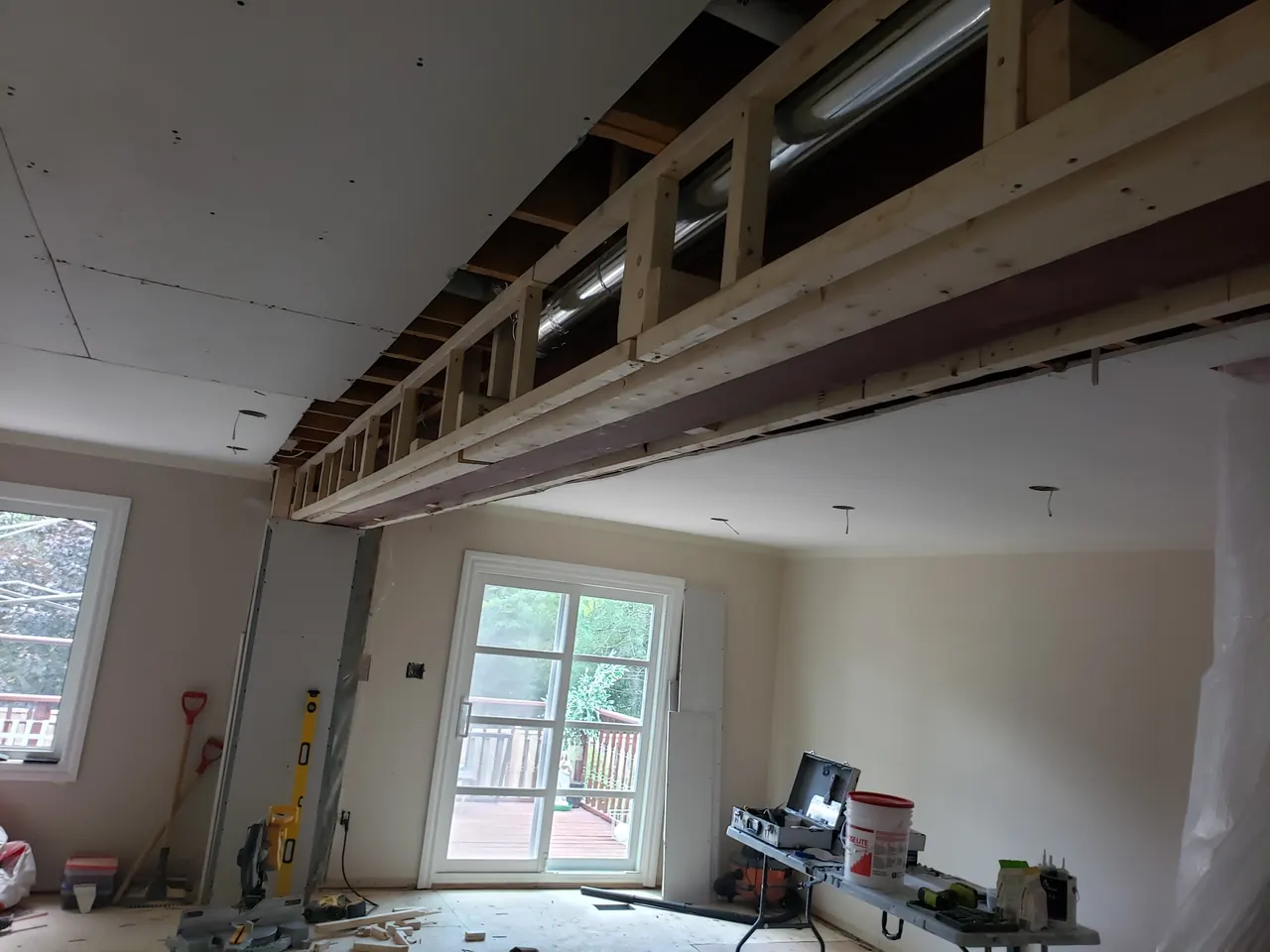 Main floor mid-renovation: a flush structural beam with the ductwork routed through it, above the new patio doors.